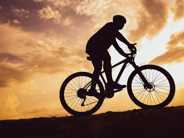 Bicicleta de montaña silueta de entrenamiento en las altas montañas por la noche, hermosos colores. - Foto, Imagen