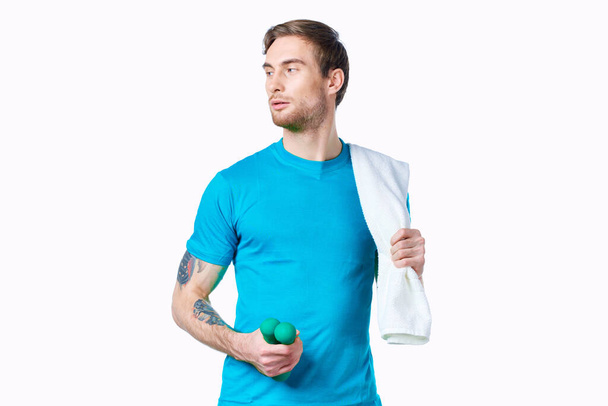 homem com halteres em mãos toalha no ombro treino fitness fundo luz - Foto, Imagem