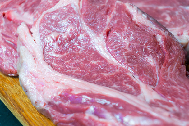 Raw marbled beef steak. Close-up photo on dark background. - 写真・画像