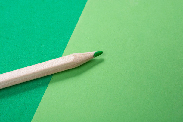 A closeup shot of a green pencil on a green paper texture - Foto, imagen