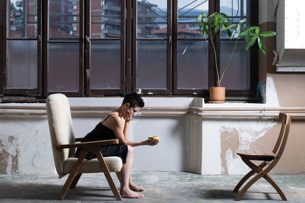 woman sitting on a profile armchair with a window behind - 写真・画像