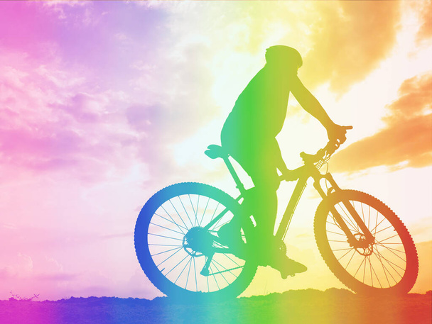 Side view of an active athlete riding a mountain bike on a bike path in the forest in the middle of nature during the colorful sunset. A young man in an exercise suit riding a bicycle on the off-road track. - Photo, Image