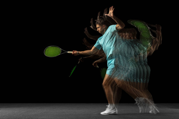 Effet stroboscope. Un homme, joueur de tennis professionnel isolé sur fond noir dans une lumière au néon mixte. - Photo, image