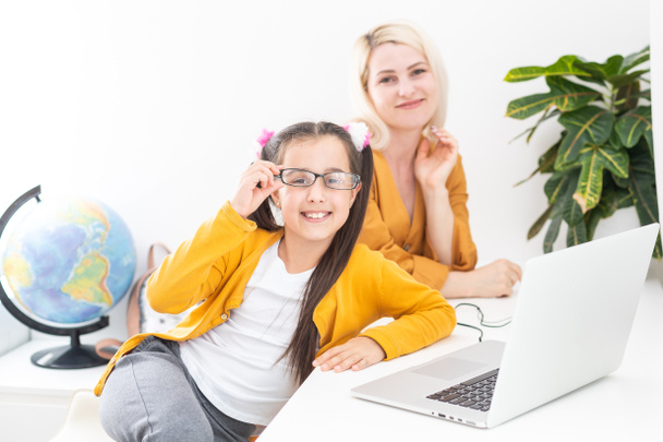 Private lesson. Attentive young woman tutor teacher help little girl pupil with studying math language correct mistakes explain learning material. Smiling mother assist small daughter with home task - Zdjęcie, obraz