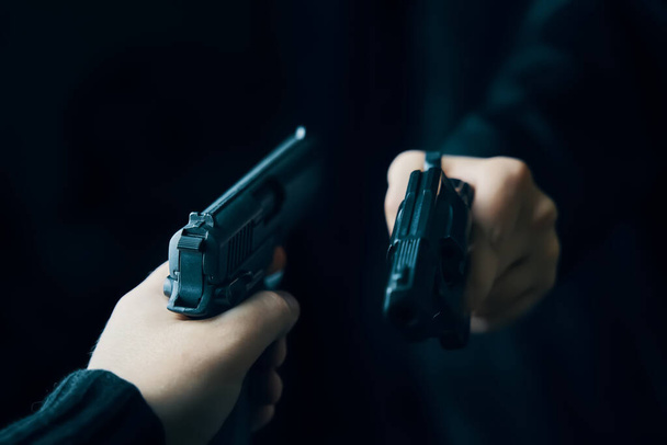 Две мужские руки с оружием, направленным друг на друга. - Фото, изображение