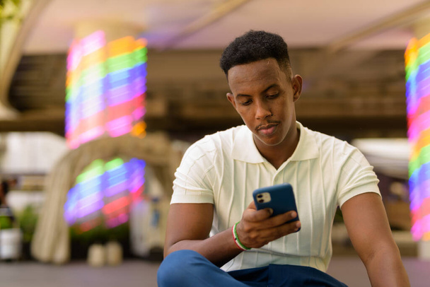 Portrait of confident young African businessman wearing casual clothes and using mobile phone - Photo, Image