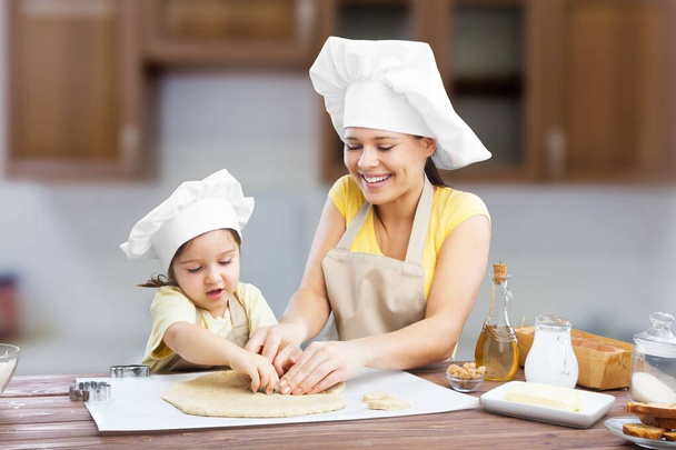 Smiling women and a child have fun baking together with dough at home kitchen. - Fotografie, Obrázek