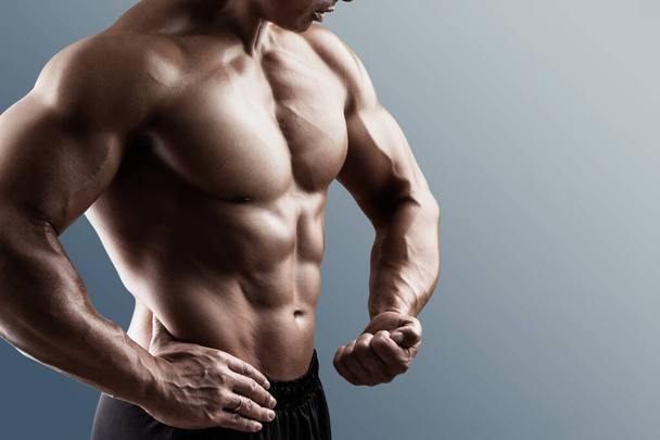 Hot young handsome sportsman bodybuilder posing on a background - Фото, изображение