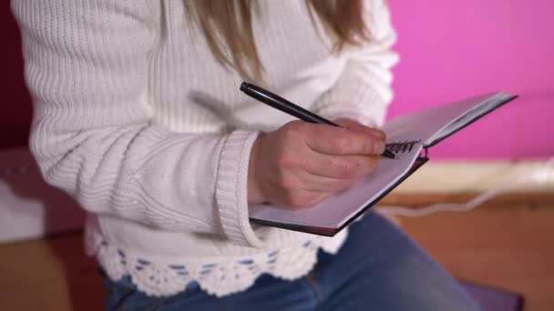 Kobieta pisze w swoim papierowym pamiętniku długopisem - Materiał filmowy, wideo