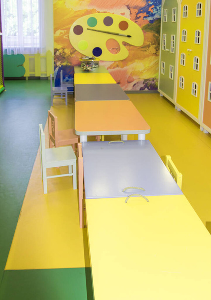 テーブルが列に並んでいるモダンな子供部屋、幼稚園のプレイルームでの描画やゲームのための場所 - 写真・画像