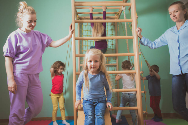 Teacher supports children during active games at preschool - Photo, image