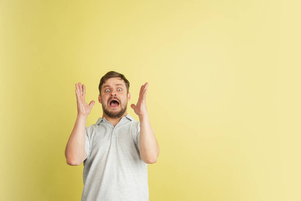 Half-length portrait of young Caucasian man isolated on light yellow background. - 写真・画像