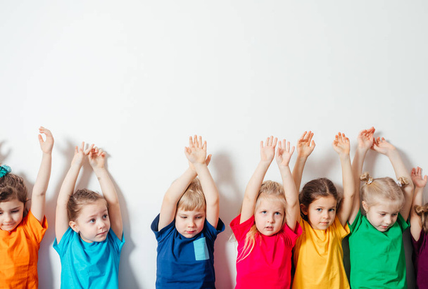 Children holding hands up on white wall background - Photo, Image