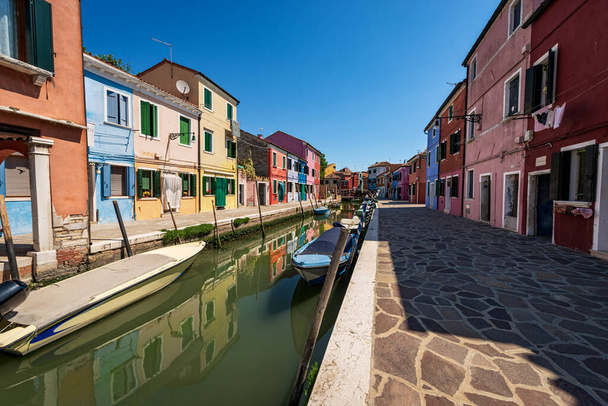 Burano island in a sunny spring day, Venice lagoon, with the multi colored houses and a canal with small boats moored. UNESCO world heritage site, Veneto, Italy, Europe. - Photo, Image