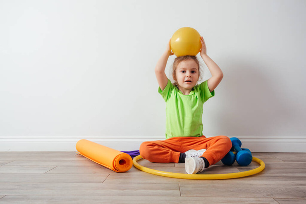 Cute boy with sport equipment sitting on a floor - Photo, Image