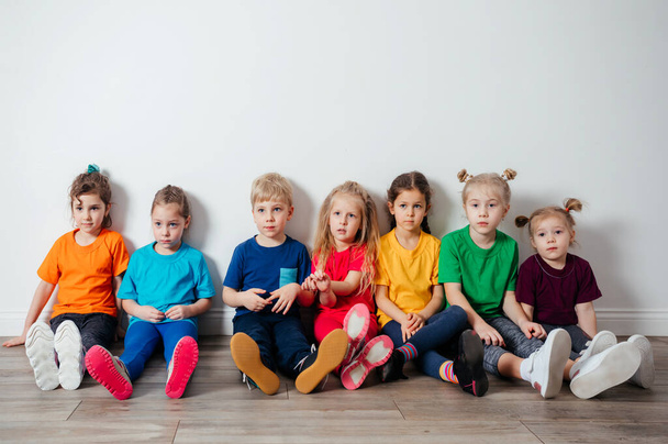 Cheerful children sitting on a floor near the wall - Foto, Bild