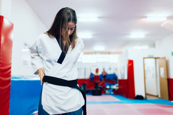 Young woman dresses in her taekwondo suit - Photo, Image