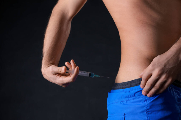 Man injecting himself on black background, closeup. Doping concept - Фото, зображення