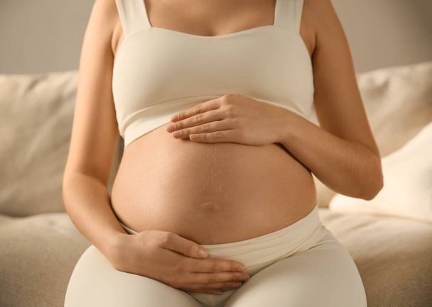 Schwangere berührt ihren Bauch drinnen, Nahaufnahme - Foto, Bild