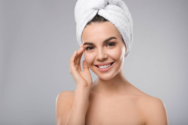 Happy young woman with towel on head against light grey background. Washing hair - Foto, immagini