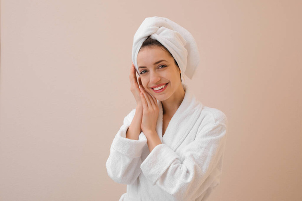 Piękna młoda kobieta z włosami owiniętymi w ręcznik po myciu na beżowym tle - Zdjęcie, obraz
