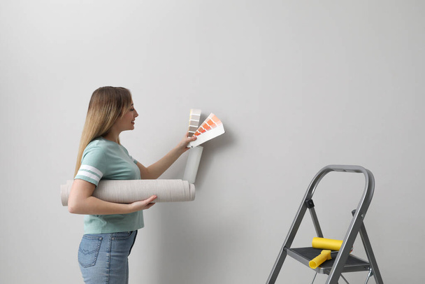 Woman with palette choosing wall paper color indoors - Foto, Imagen