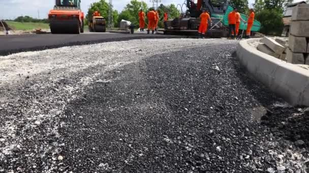 Visão de baixo ângulo em trabalhadores e máquinas para a colocação de asfalto, espalhando camada de asfalto quente em solo preparado. - Filmagem, Vídeo