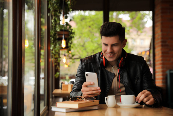 Man with headphones and smartphone at table in cafe - Foto, Bild