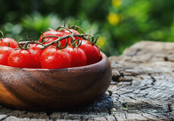 Cherry tomatoes in heart shape plate on old wooden surface, space for text. Natural light, close up, selective focus. - Foto, afbeelding