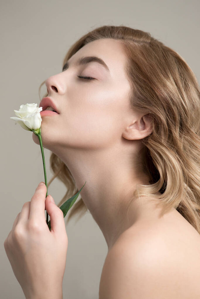 Beautiful young woman with perfect skin, natural make up and flower. Fashion model with nice professional make-up posing in the studio. SPA, wellness, bodycare and skincare concept. - Foto, Imagen
