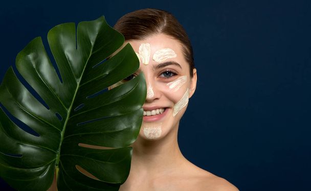 Young woman with stroke of facial mask at her face. Beauty model with perfect fresh skin and long eyelashes cares about her skin at home. Spa and Wellness, Skin Care Concept. Close up, selected focus. - Fotografie, Obrázek