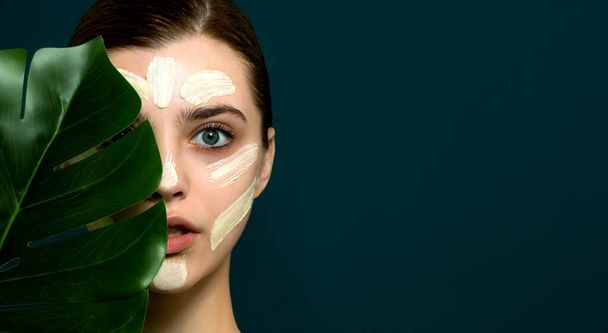 Young woman with stroke of facial mask at her face. Beauty model with perfect fresh skin and long eyelashes cares about her skin at home. Spa and Wellness, Skin Care Concept. Close up, selected focus. - Foto, Bild