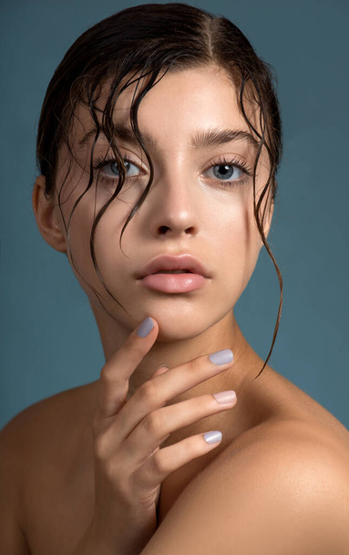 Beautiful young  woman with fresh clean perfect skin. Portrait of beauty model with natural make up with wet skin and hair and hand with manicure touching face. Spa, skincare and wellness. - Fotó, kép