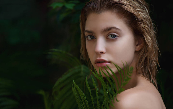 Beautiful young woman with perfect skin  front of plant tropical green leaves background with fern. SPA, wellness, bodycare and skincare.  Close up, selective focus. - Photo, image