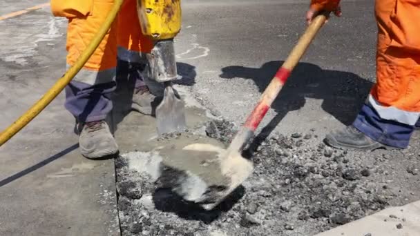 Trabalhador da construção quebra asfalto com um martelo pneumático. Homem usando pá para pegar e jogar fora partes rachadas. - Filmagem, Vídeo