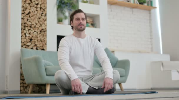 Hombre joven meditando en la esterilla de yoga en casa - Metraje, vídeo