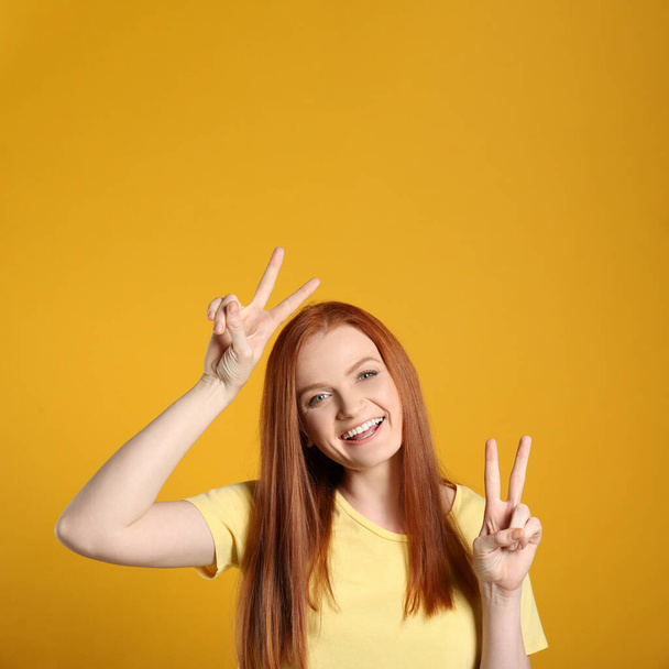 Portrait of cheerful young woman with gorgeous red hair posing on yellow background - Photo, Image
