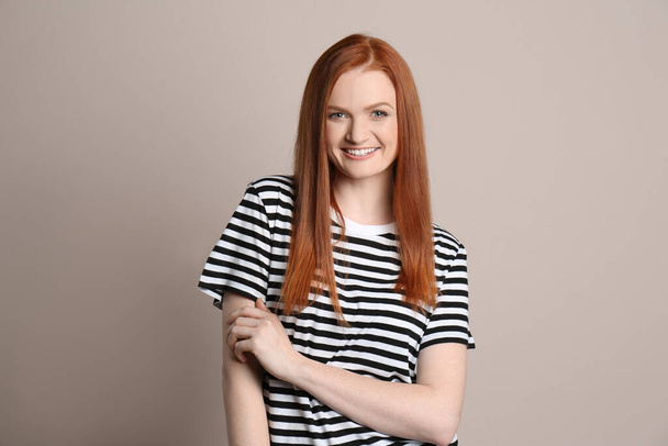 Candid portrait of happy young woman with charming smile and gorgeous red hair on beige background - Valokuva, kuva