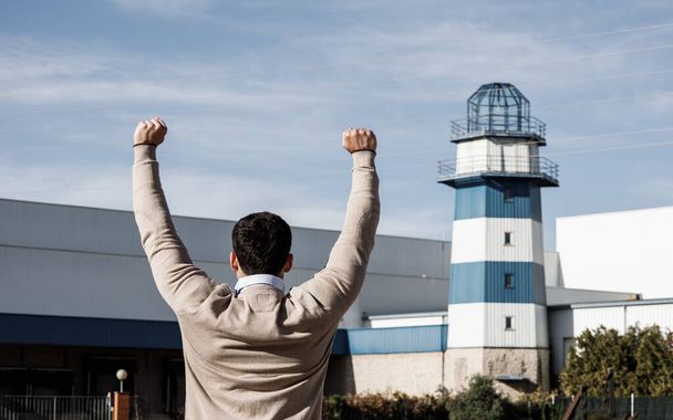 Worker celebrating victory over a lighthouse. End of the pandemic. Shot from the back. - Photo, Image