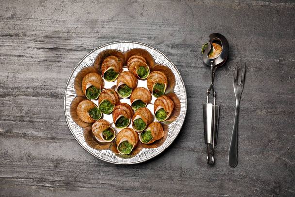 Delicious cooked snails served on grey table, flat lay - 写真・画像