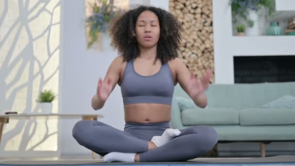 Nuori afrikkalainen nainen meditoi joogamatolla kotona - Materiaali, video