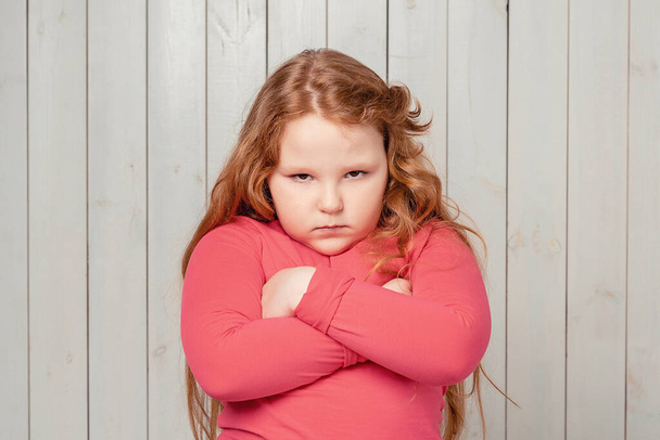 Angry with you. Portrait of moody displeased redhead preteen girl in casual clothes, crossing arms on her chest, looking at camera. Studio shot, light wooden background - Photo, Image