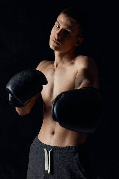 bodybuilders boxing gloves on black background and gray pants - Foto, imagen