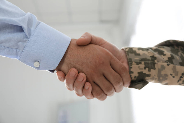 Soldier and businessman shaking hands indoors, closeup - Photo, Image