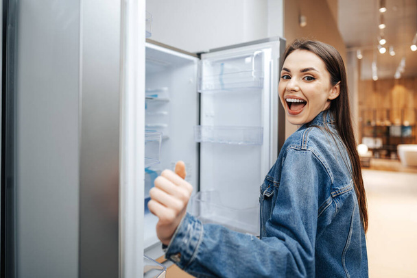Mujer atractiva joven eligiendo refrigerador en hipermercado - Foto, imagen