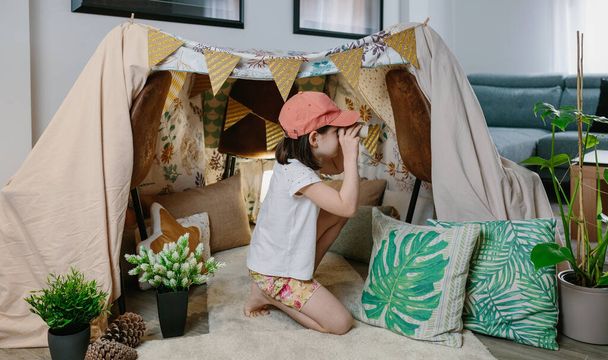 Girl playing with cardboard binoculars while camping at home - Φωτογραφία, εικόνα