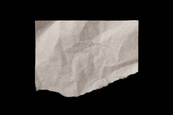 Torn crumpled beige paper sheet isolated on blackbackground - Photo, image