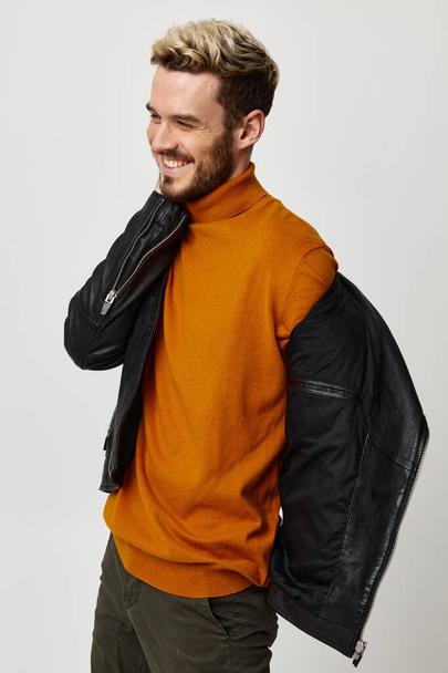 幸せなブロンド男でオレンジ色のセーターと革のジャケット見ますザサイドクロップドビュー - 写真・画像
