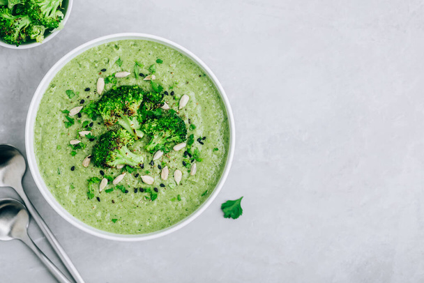 Brokkoli krémleves napraforgóval és szezámmaggal. Zöld vegetáriánus nyári leves, felülnézet. - Fotó, kép