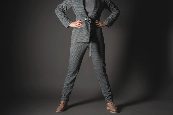 Confident business woman is standing with her arms on her belt on a gray background. - Foto, afbeelding